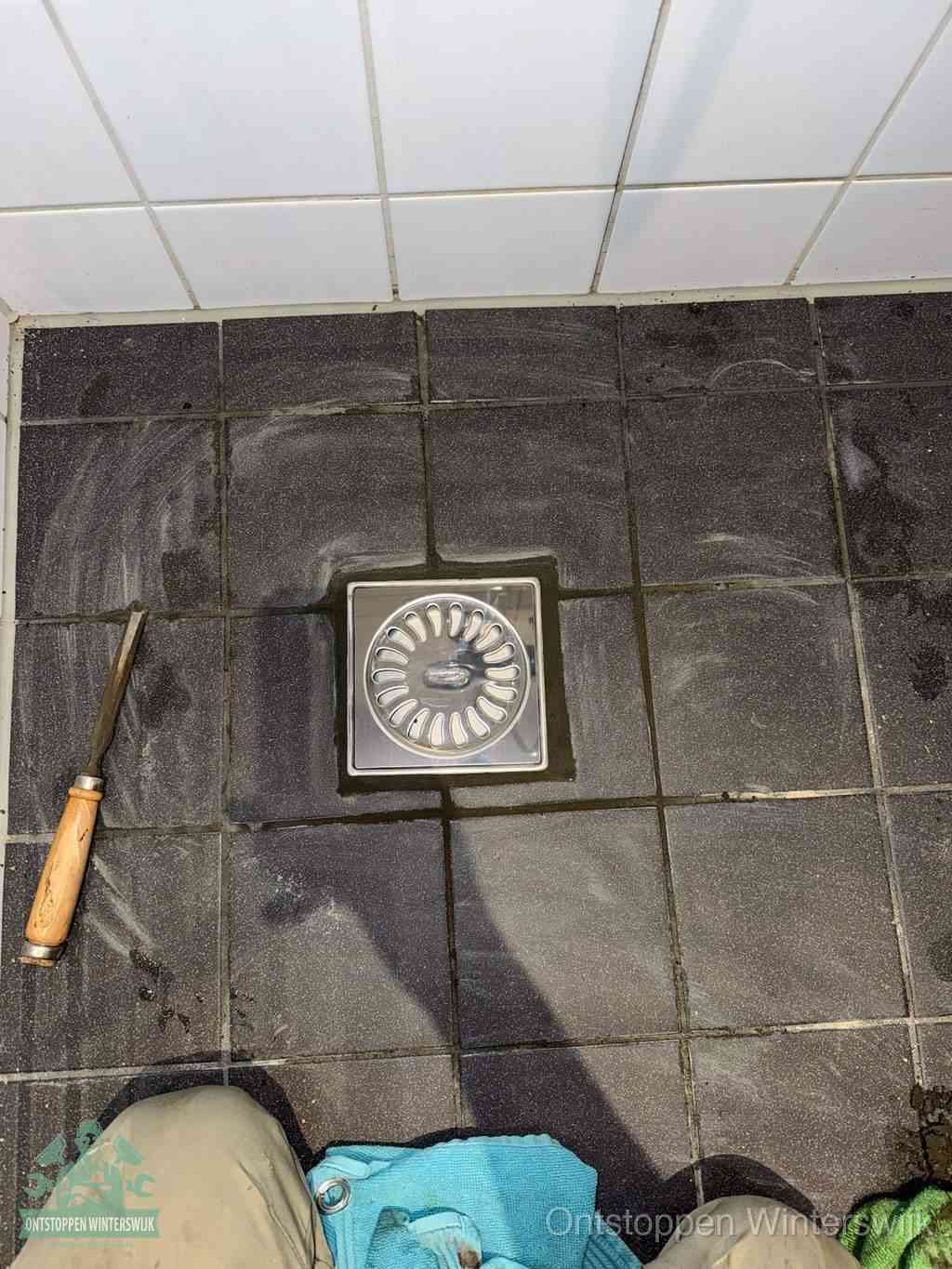 Een RVS doucheputje in een betegelde badkamervloer, zelf je badkamer ontstoppen in Winterswijk