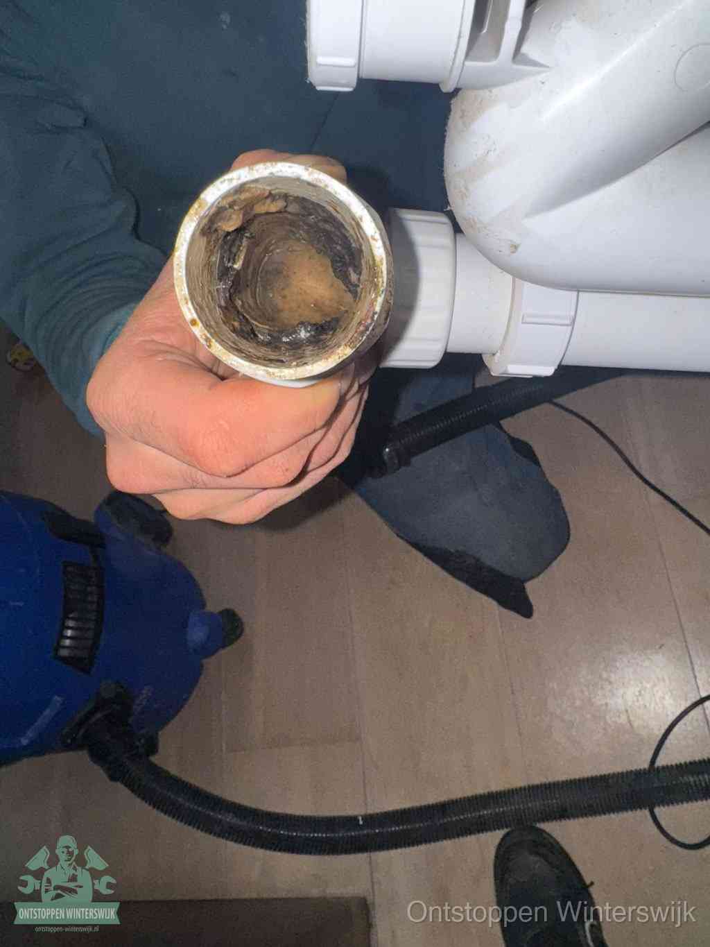 Een losgekoppeld PVC-afvoerbuisstuk dat van binnen volledig is dichtgeslibd met vet en vuil, de meest voorkomende oorzaak van verstoppingen in Winterswijk
