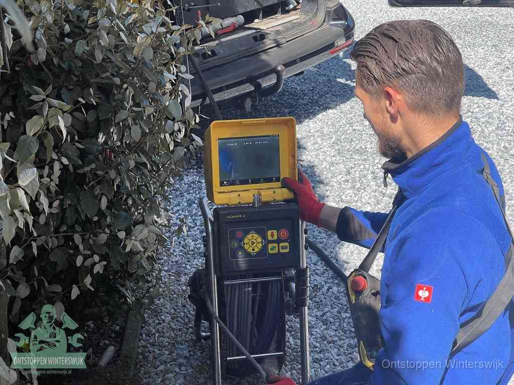 Een monteur bedient een rioolinspectiecamera met monitor en haspel om de verstopping in beeld te brengen in Winterswijk
